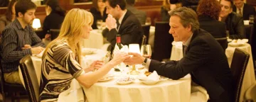 Twom People Sat Across A Dinner Table Holding Hands